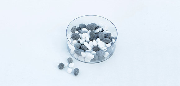 Schale mit weißen und grauen ovalen Bonbons auf weißem Hintergrund