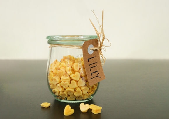 Anleitung um Snacks für Katzen selber zu backen Glasgefäß mit kleinen, gelben, herzförmigen Snacks und Namensschild