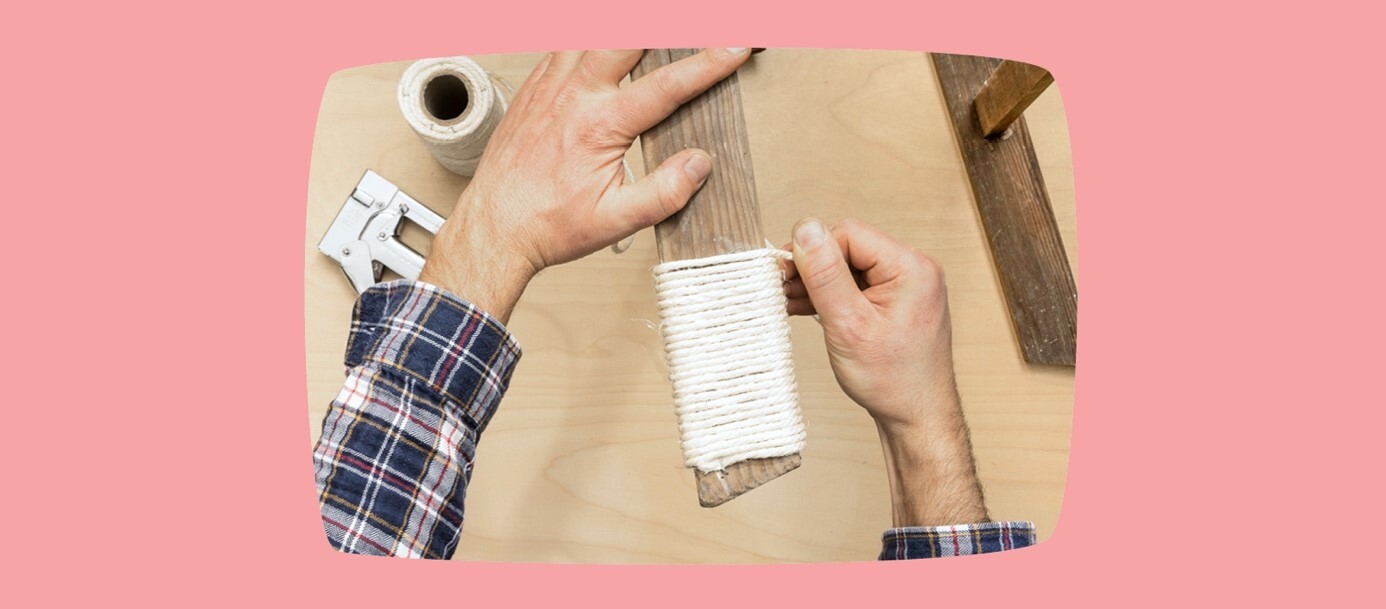 Mann wickelt weißen Seil um Holzbrett für DIY-Projekt mit Werkzeug auf Holztisch