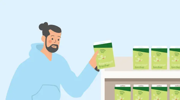 Mann mit blauer Kapuzenjacke hält eine Packung Fressnapf Tracker vor einem Regal mit mehreren grünen Fressnapf Tracker Packungen.