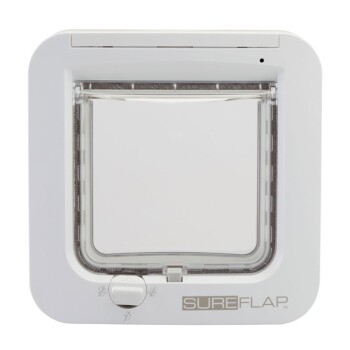 Weiße Haustiertür mit einer transparenten Klappe, mit einem Schlossmechanismus und dem Markennamen "SUREFLAP" am unteren Ende.